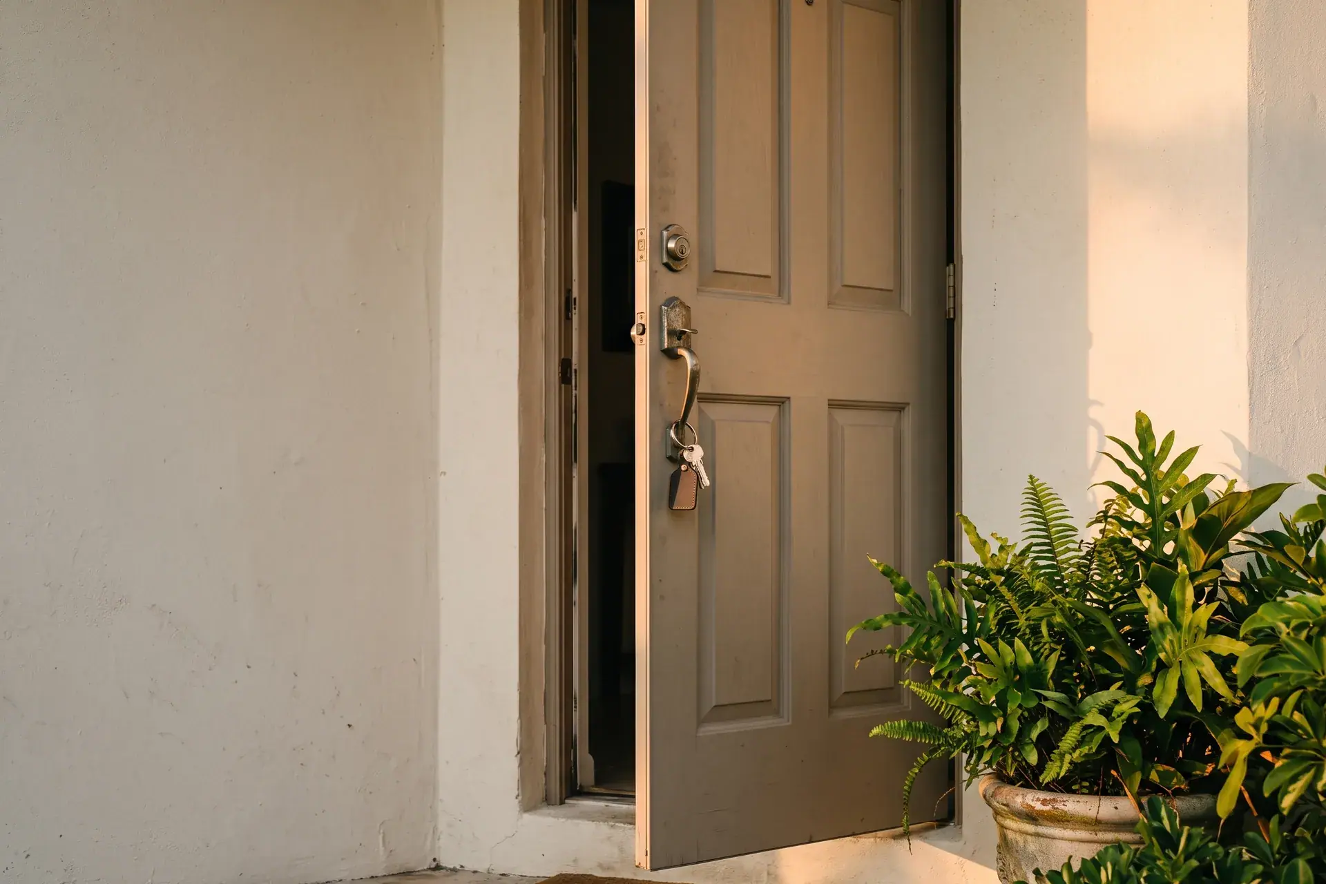 Llaves colgando de una puerta de entrada abierta con una planta al lado